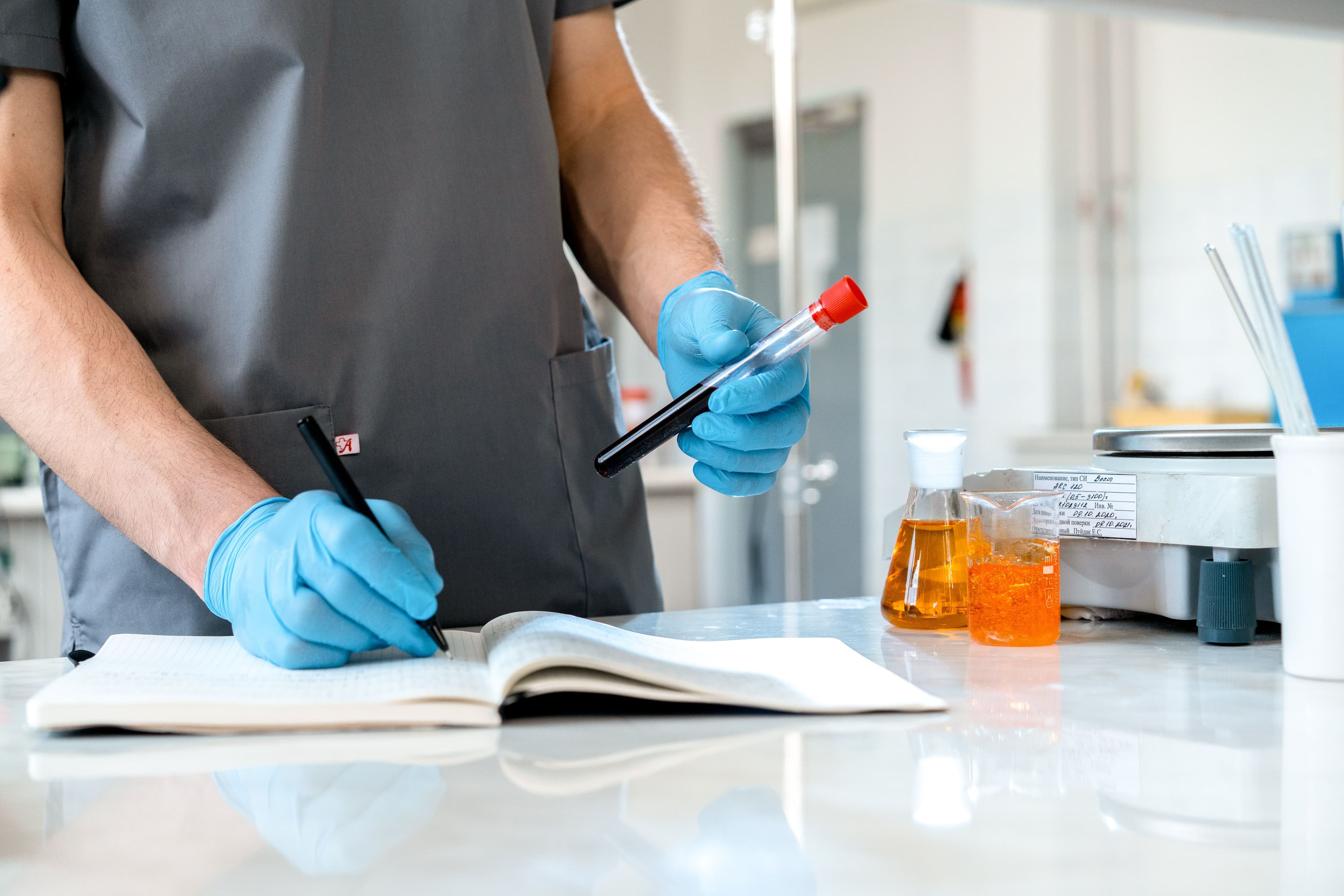 Lab technician processing samples with patient records nearby